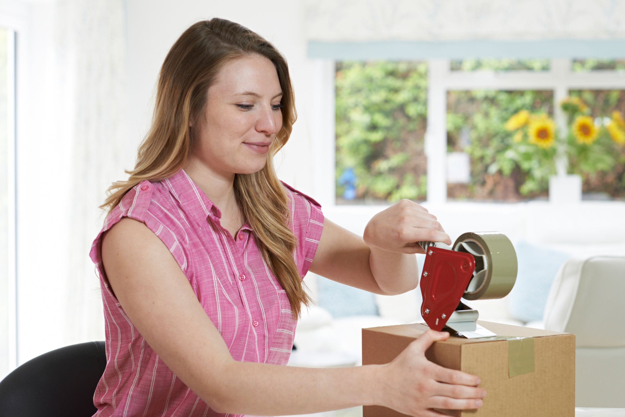 A woman puts tape on a box.