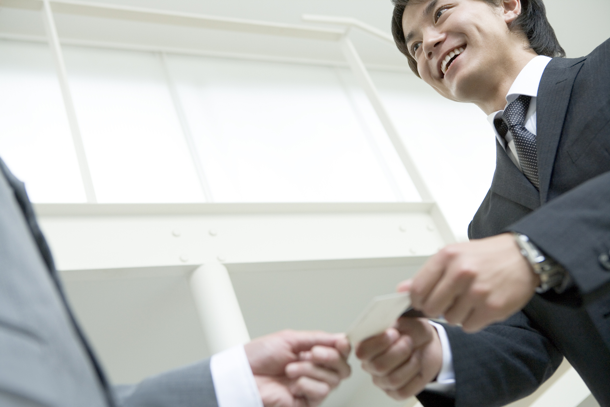 Man in suit handing business card to another man in suit