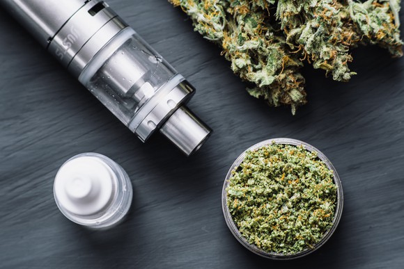 A vape pen next to neatly arranged dried cannabis flowers.