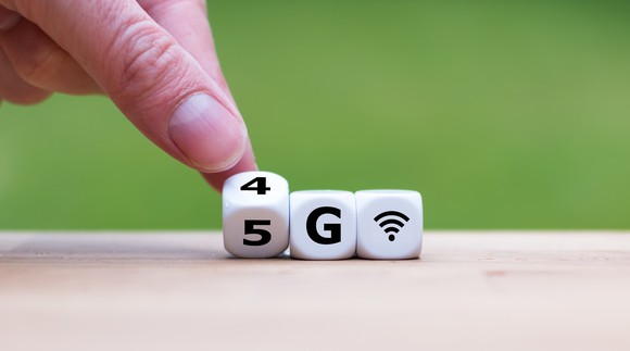 Dice spelling out '4G' being rolled over to '5G' by someone's finger
