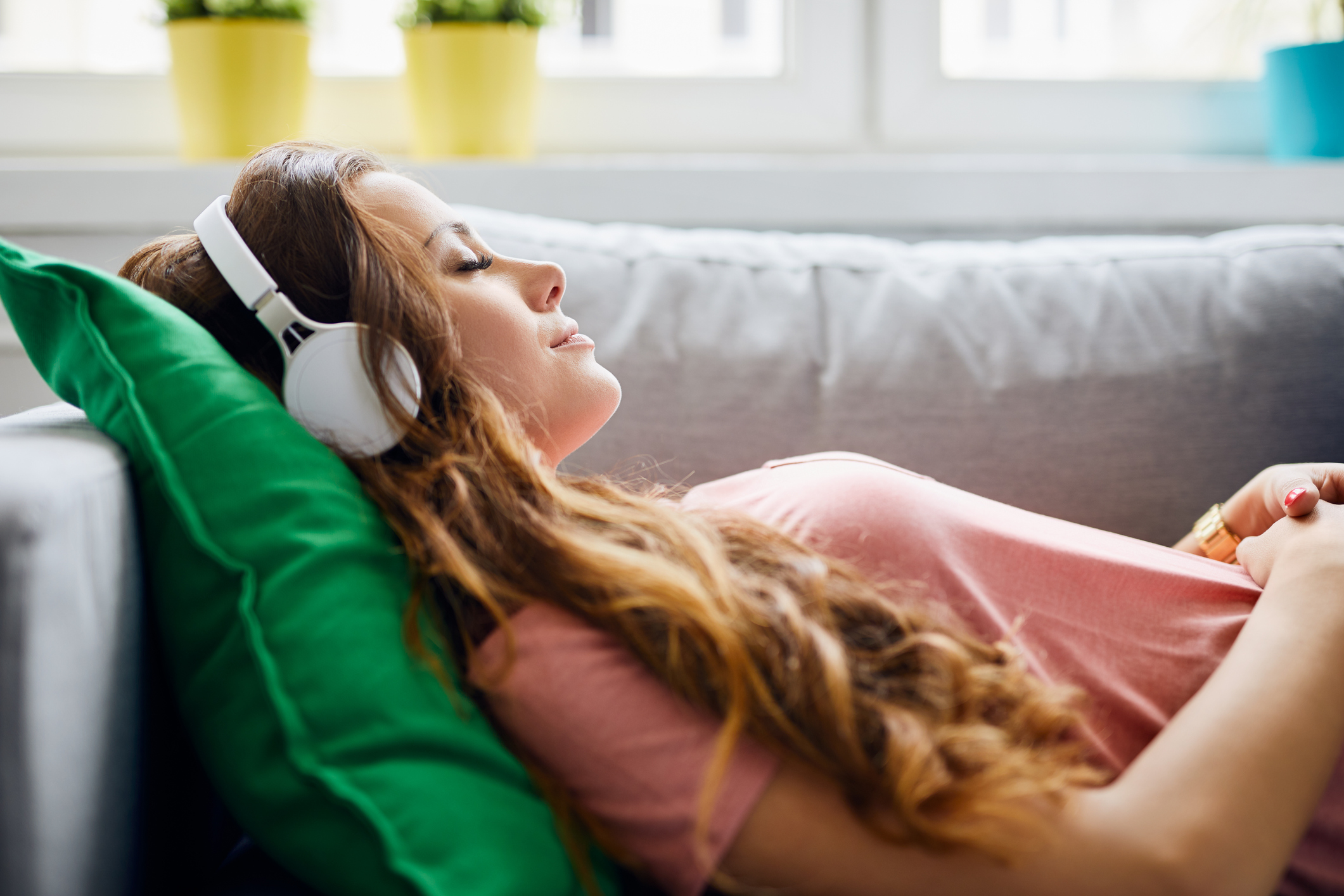 A girl laying on the couch and wearing headphones.