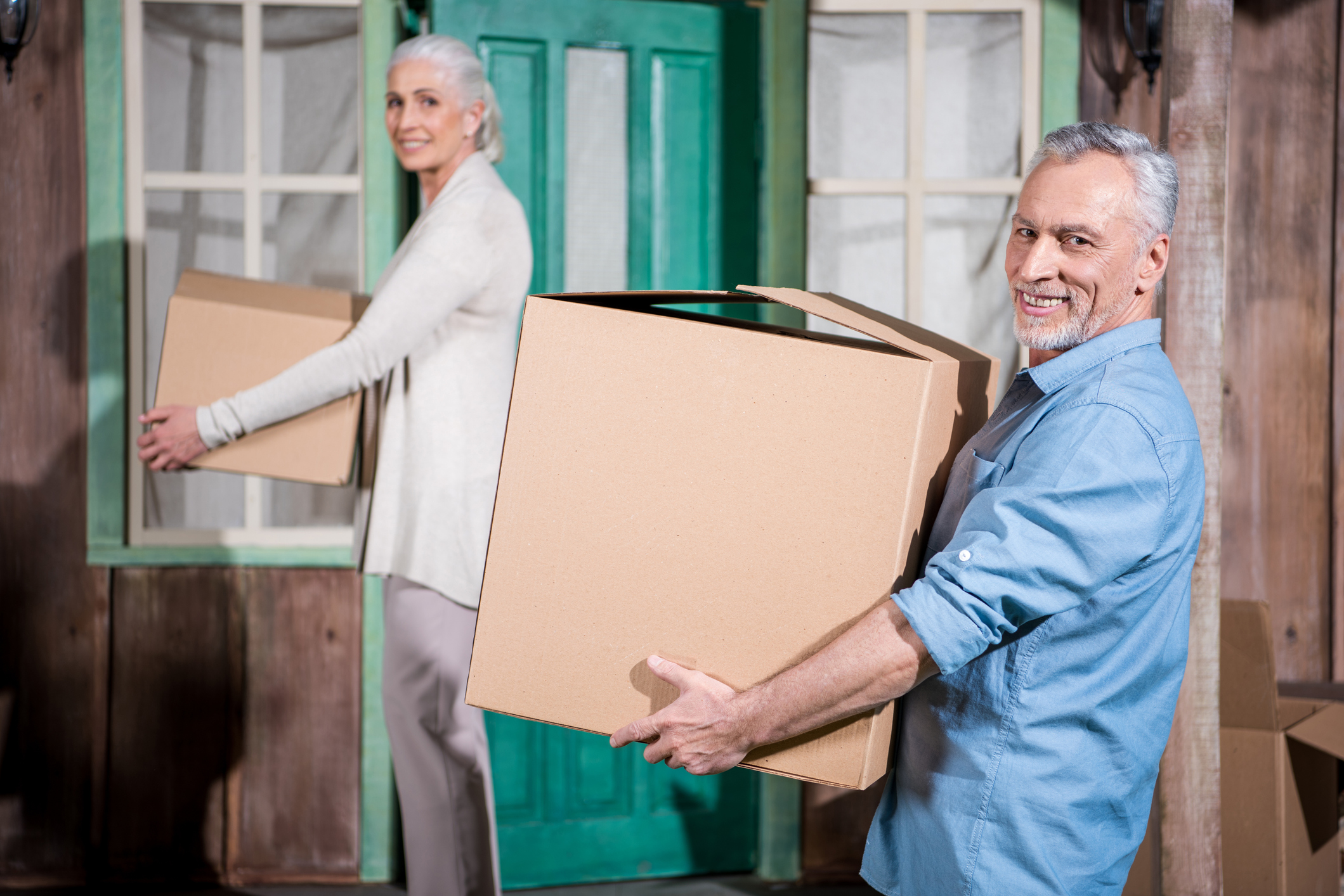 Senior man and woman carrying moving boxes