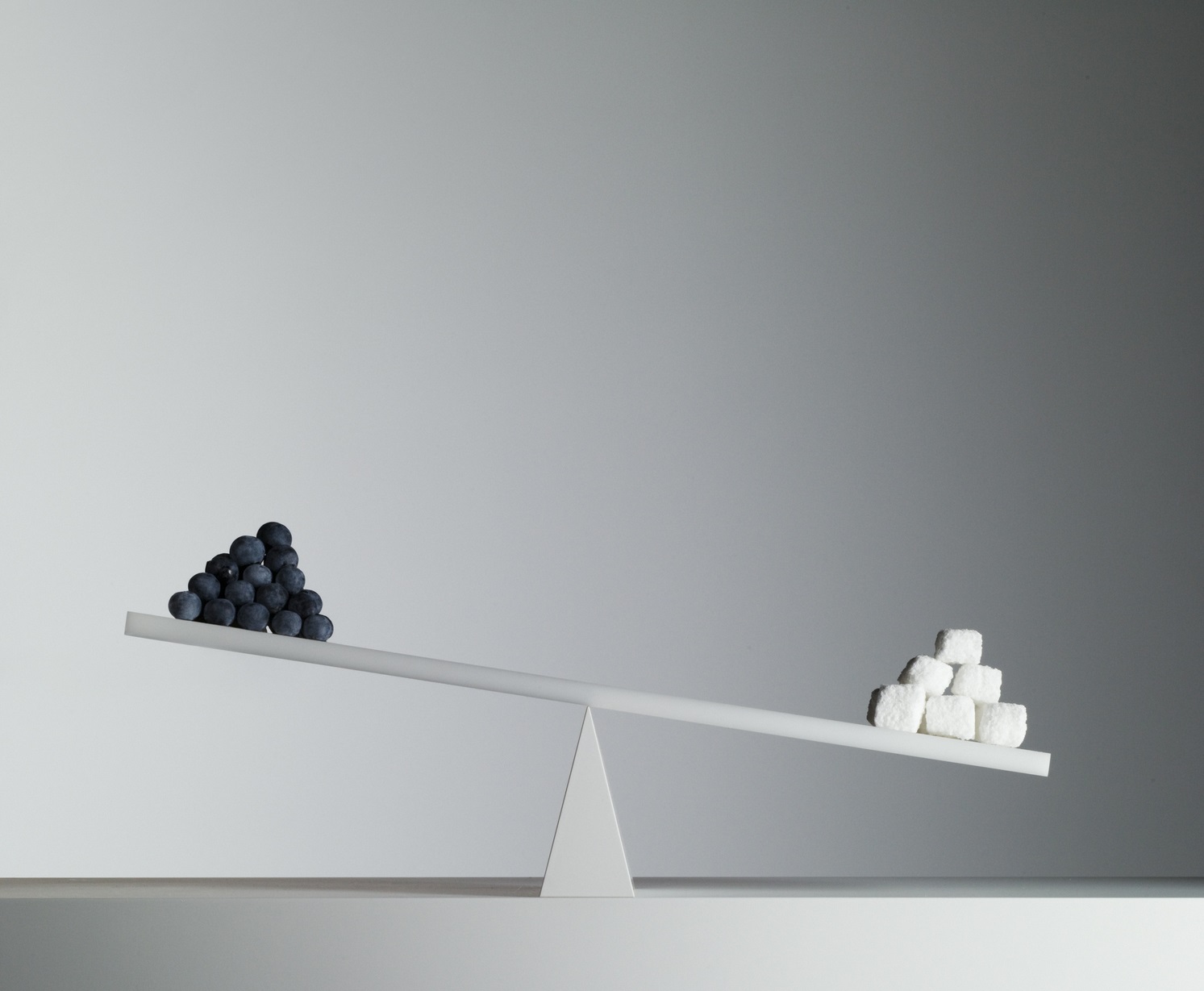 Seesaw with black pellets on one end and white cubes on the other.