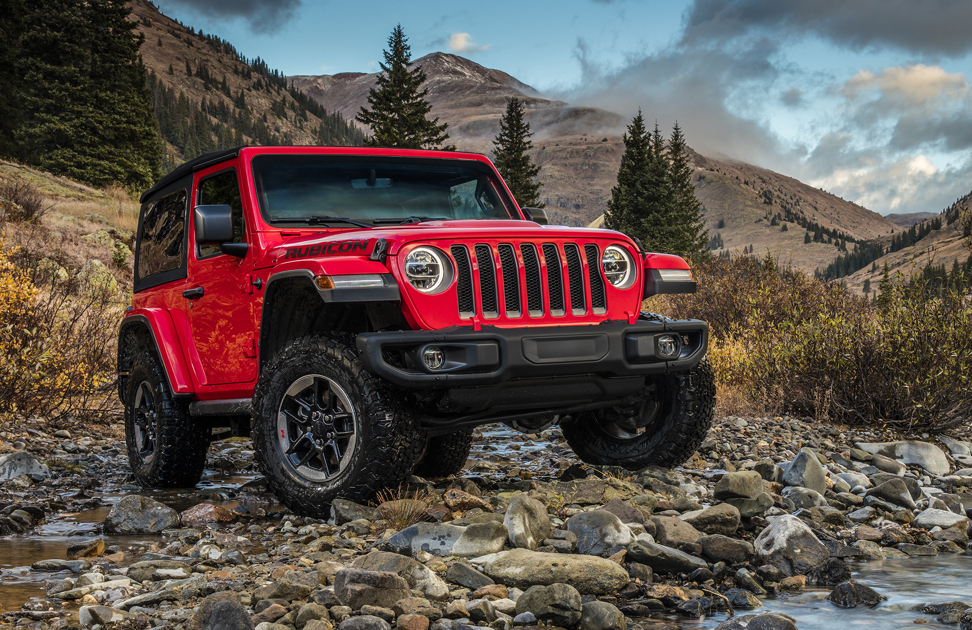A red Jeep Wrangler Rubicon, shown on a rocky trail in the mountains