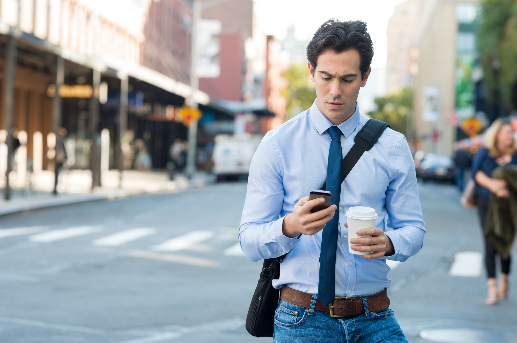 A young man looking at his phone on the street.