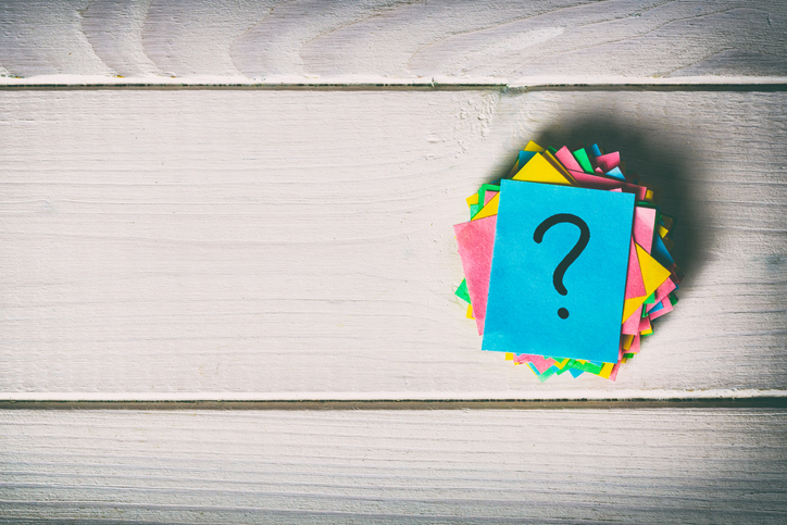 A question mark drawn on a card sitting on a table.