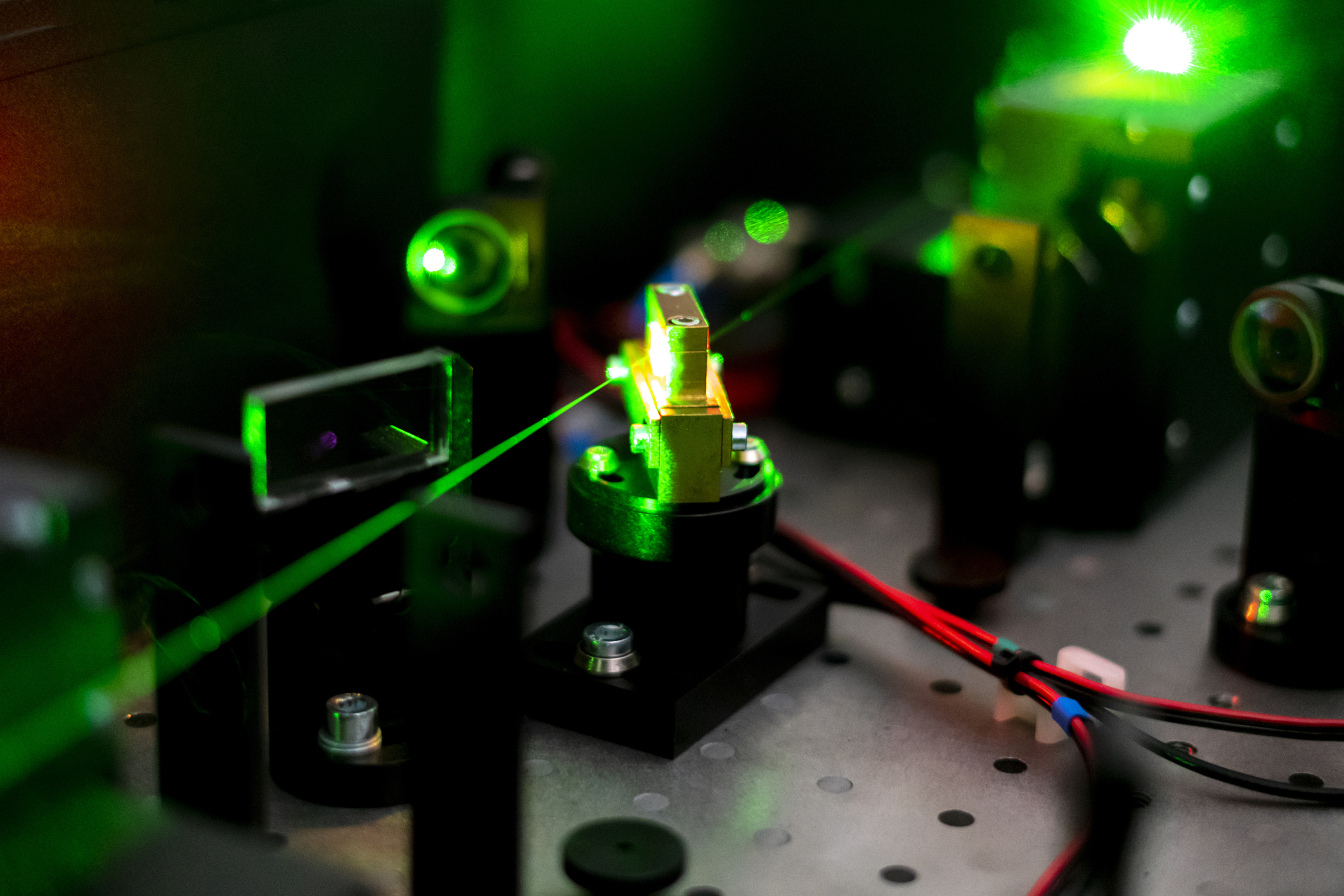 A green laser beam shines through an array of electronic circuits