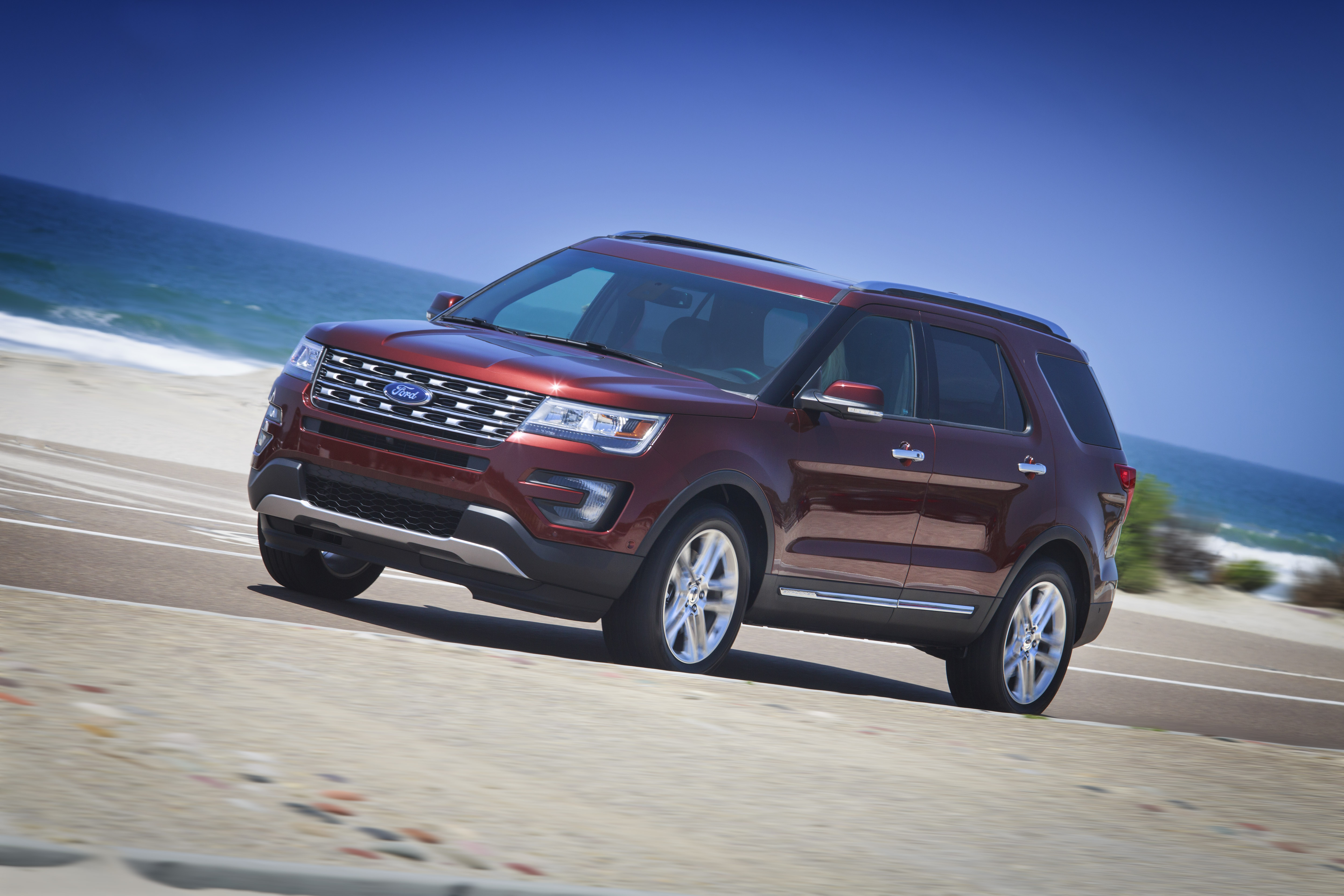 A dark red 2016 Ford Explorer, a midsize SUV, on a beach road.