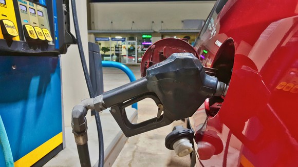 A gas pump filling up a car, with a convenience store in the background. 