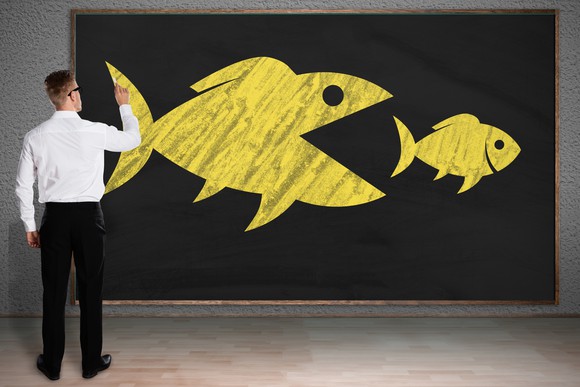 Person drawing a big fish eating a small fish.