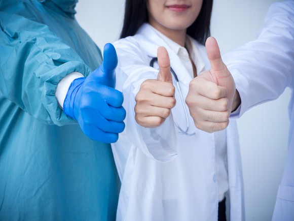 Three doctors with their thumbs up.