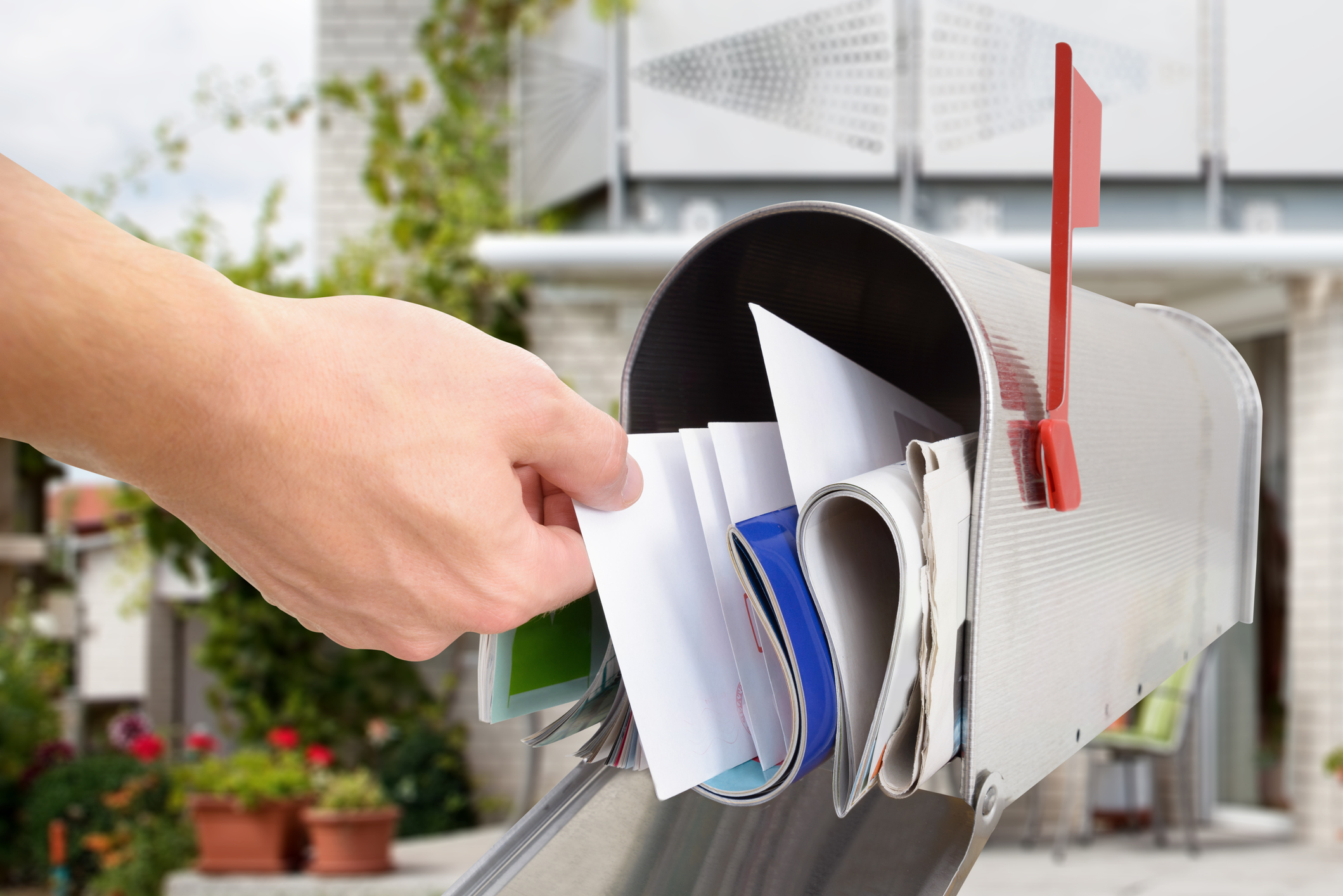 A hand reaches into a mailbox full of mail.