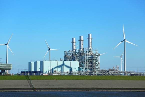A gas-fired power plant alongside some wind-powered turbines.