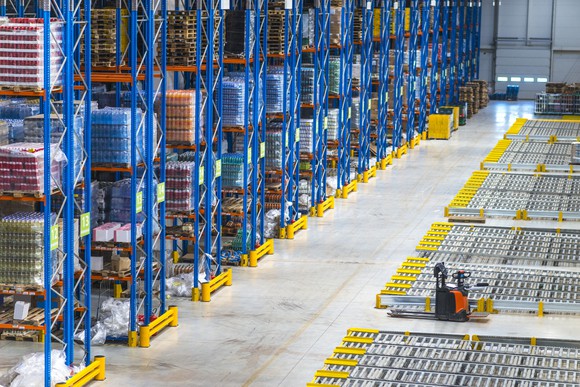 Top view of large storage area in a distribution warehouse interior with goods on the shelf and forklifts