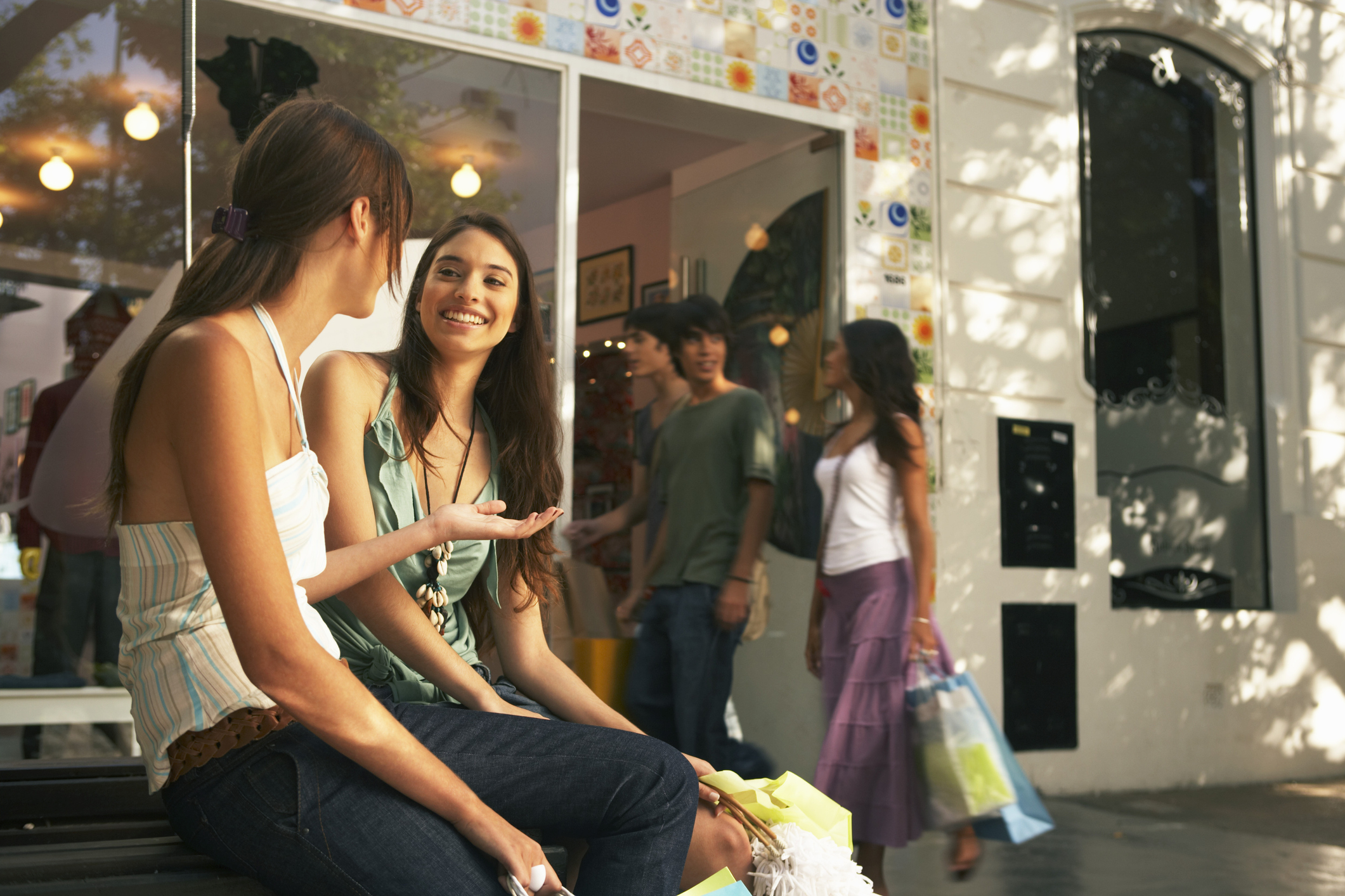 Two young women talk outside a store.
