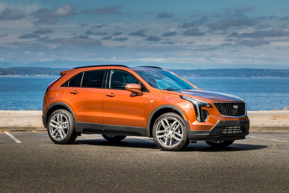 An orange Cadillac XT4 parked in front of a beach