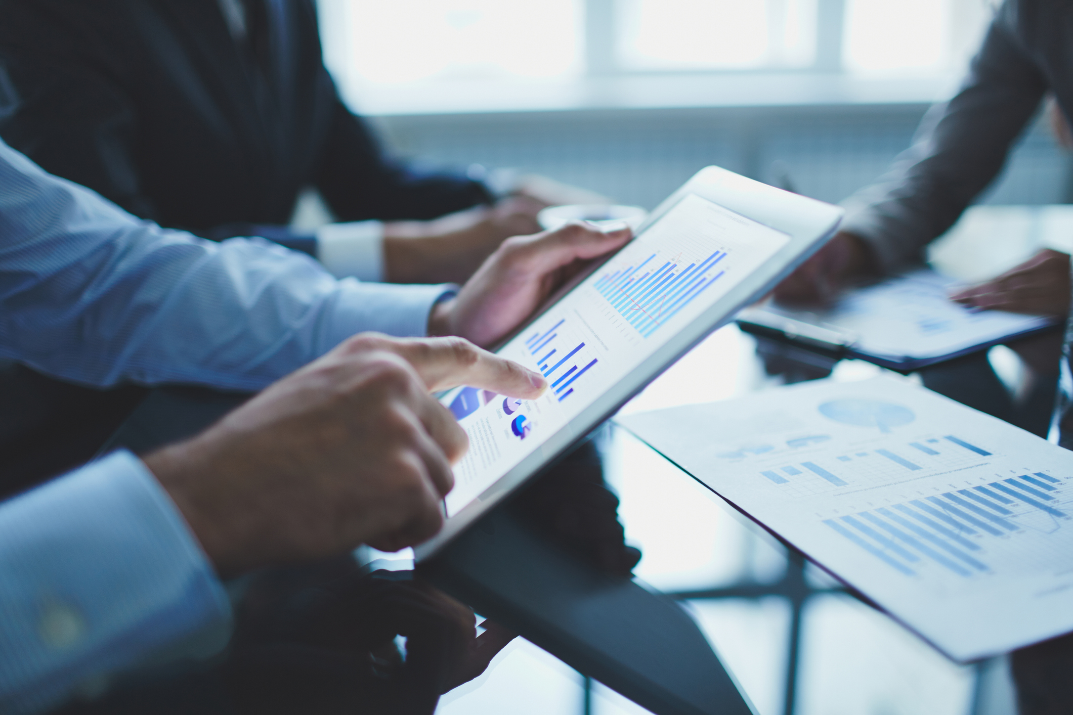 A businessman points to a financial chart on a tablet.