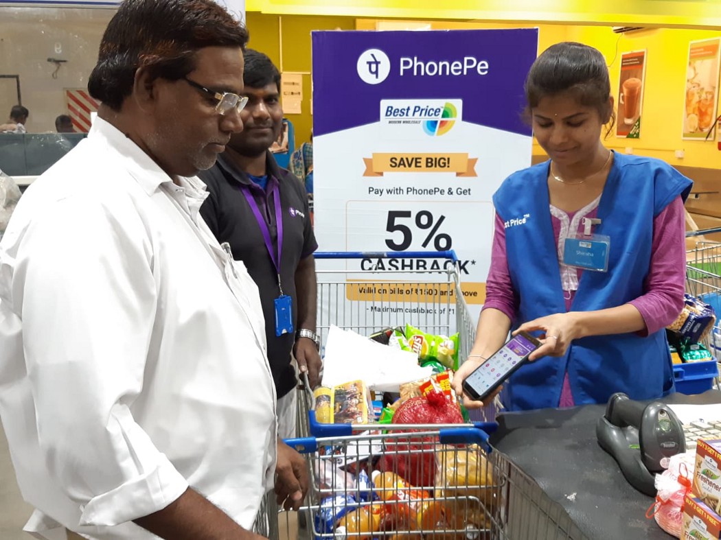 A woman scanning a basket of groceries with a smartphone.