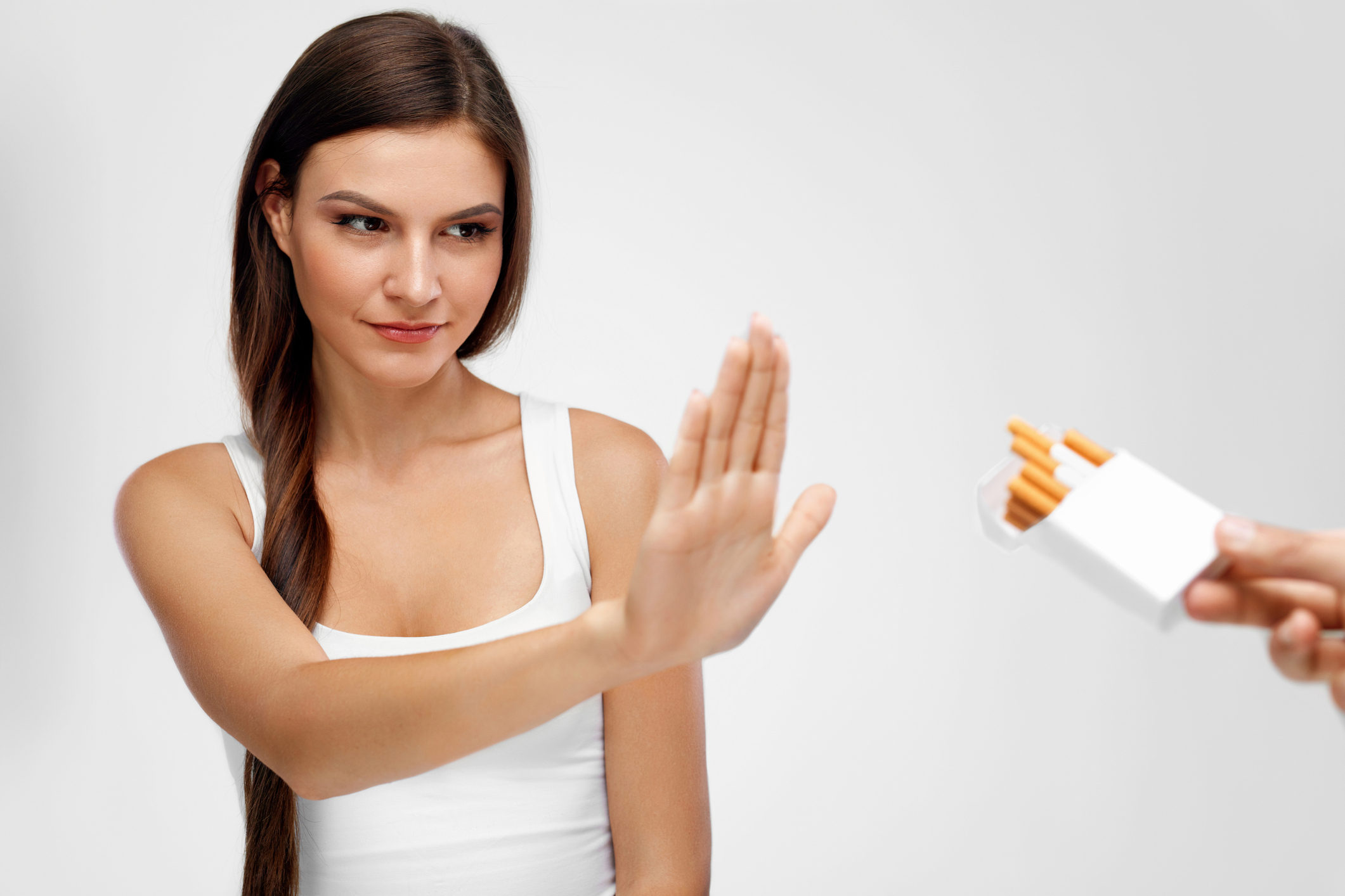 A woman rejects an offered pack of cigarettes.