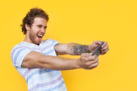 A man plays a mobile game on a smartphone.