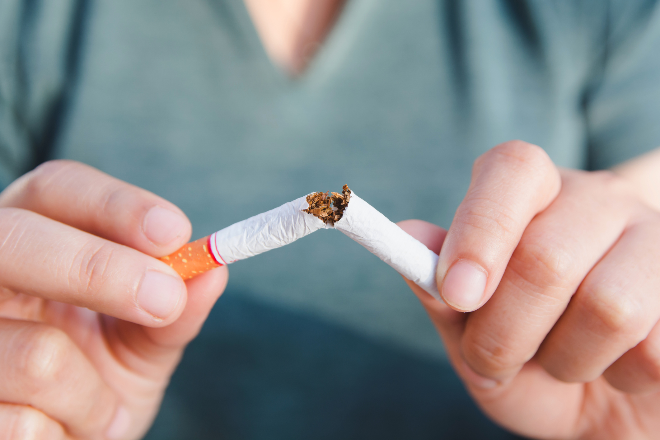 A man snaps a cigarette in half.