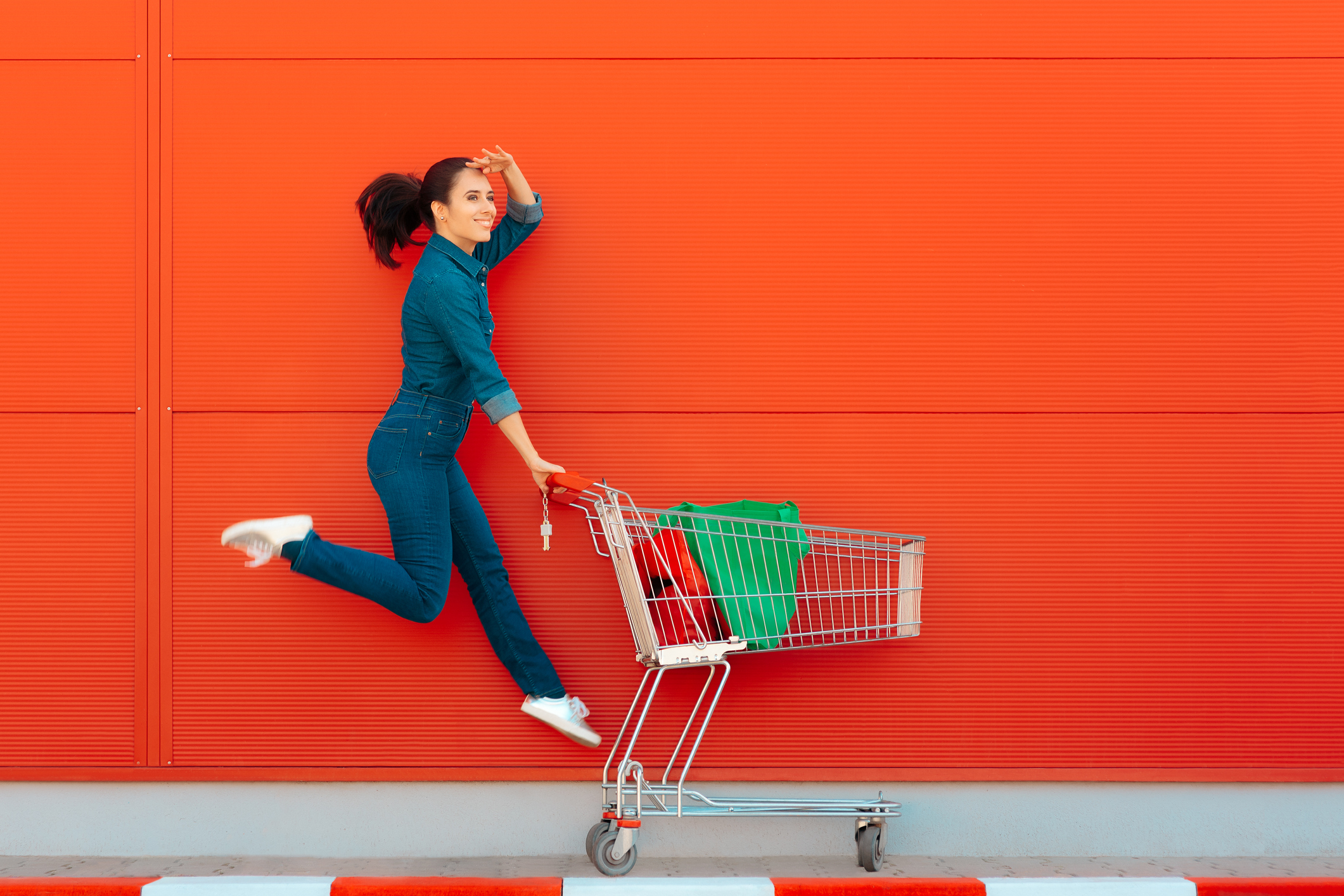 A woman skipping as she pushes a shopping cart.