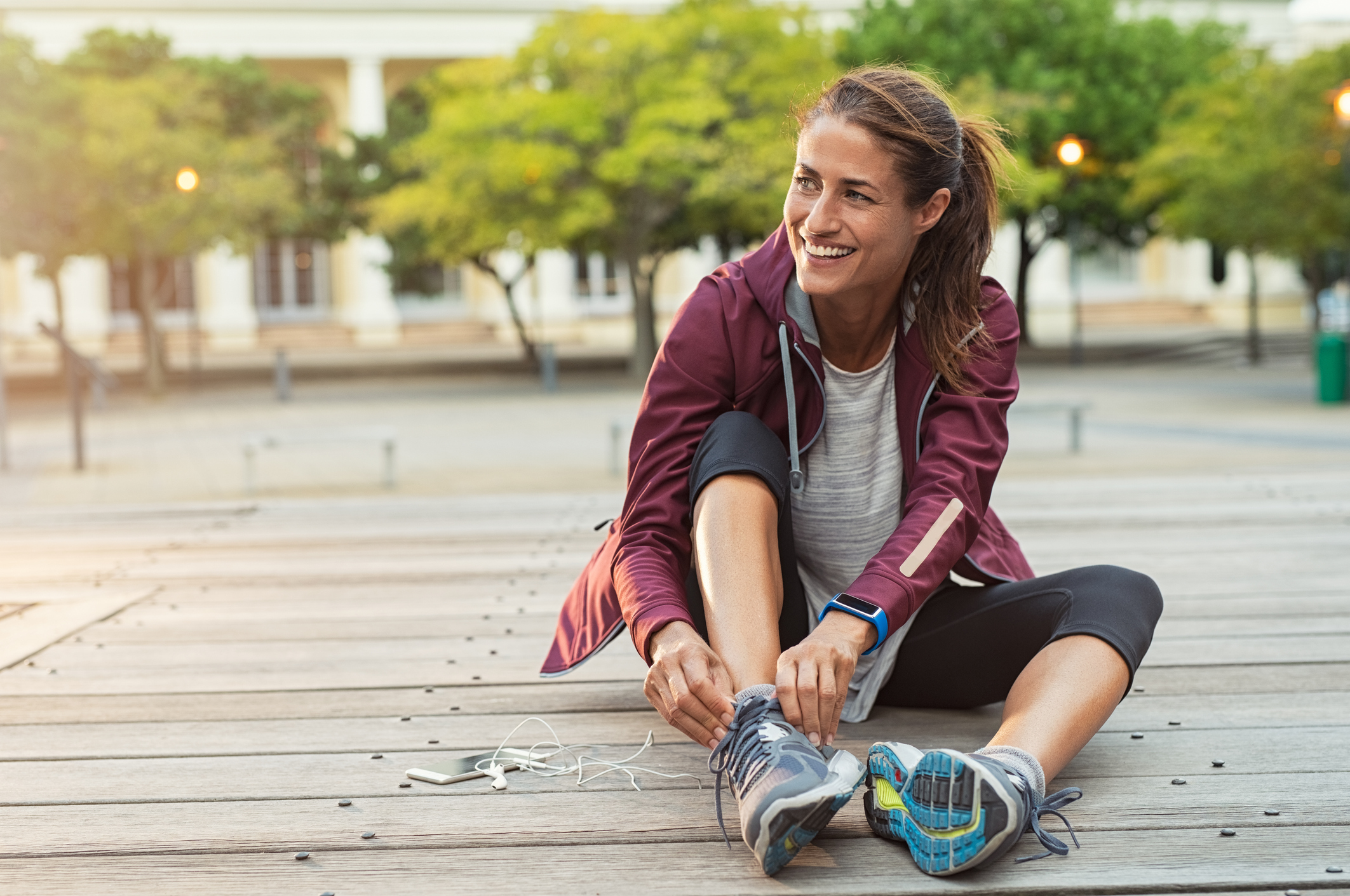 Woman sitting on the ground putting on tennis shoes