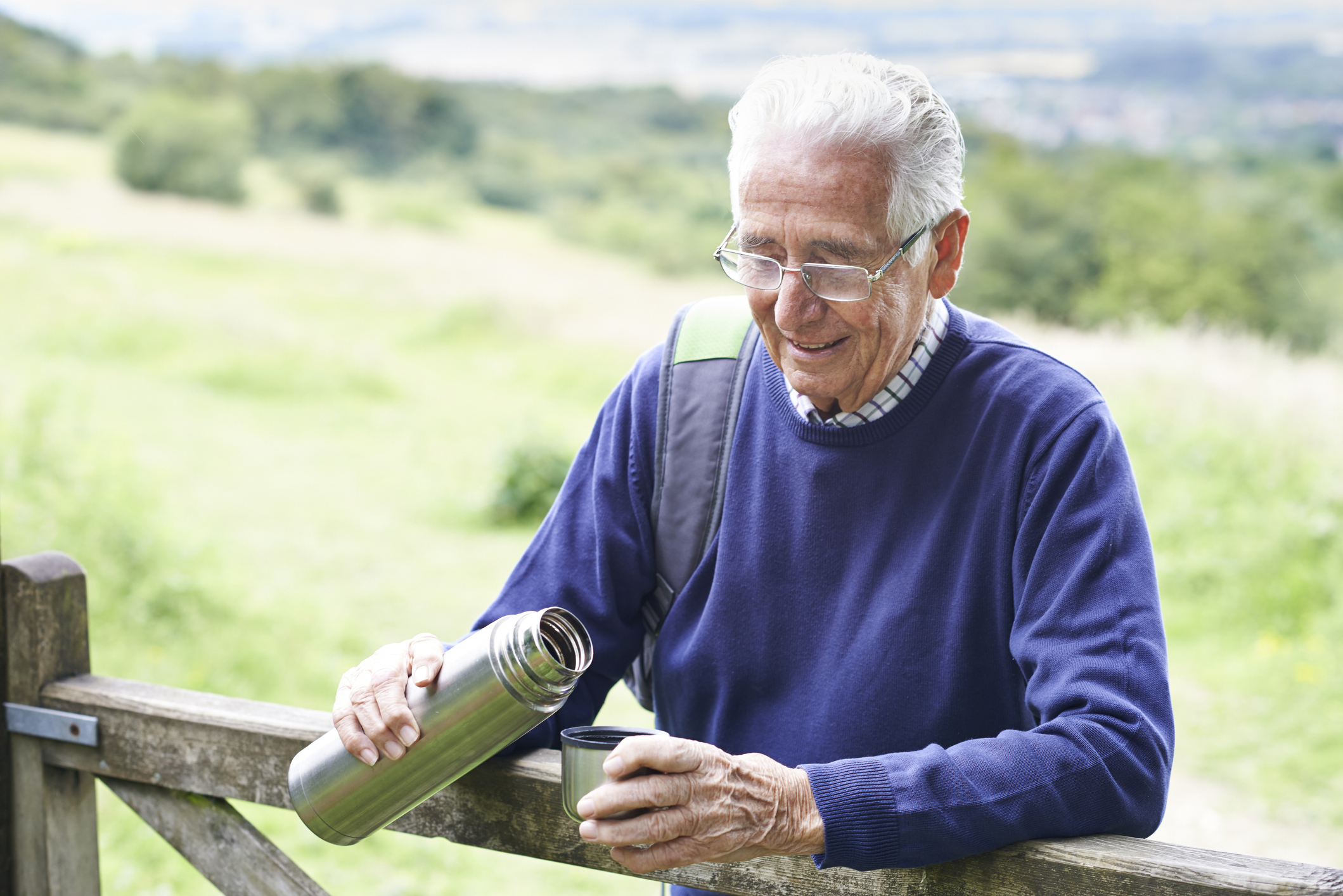 Senior man outdoors holding an open thermos