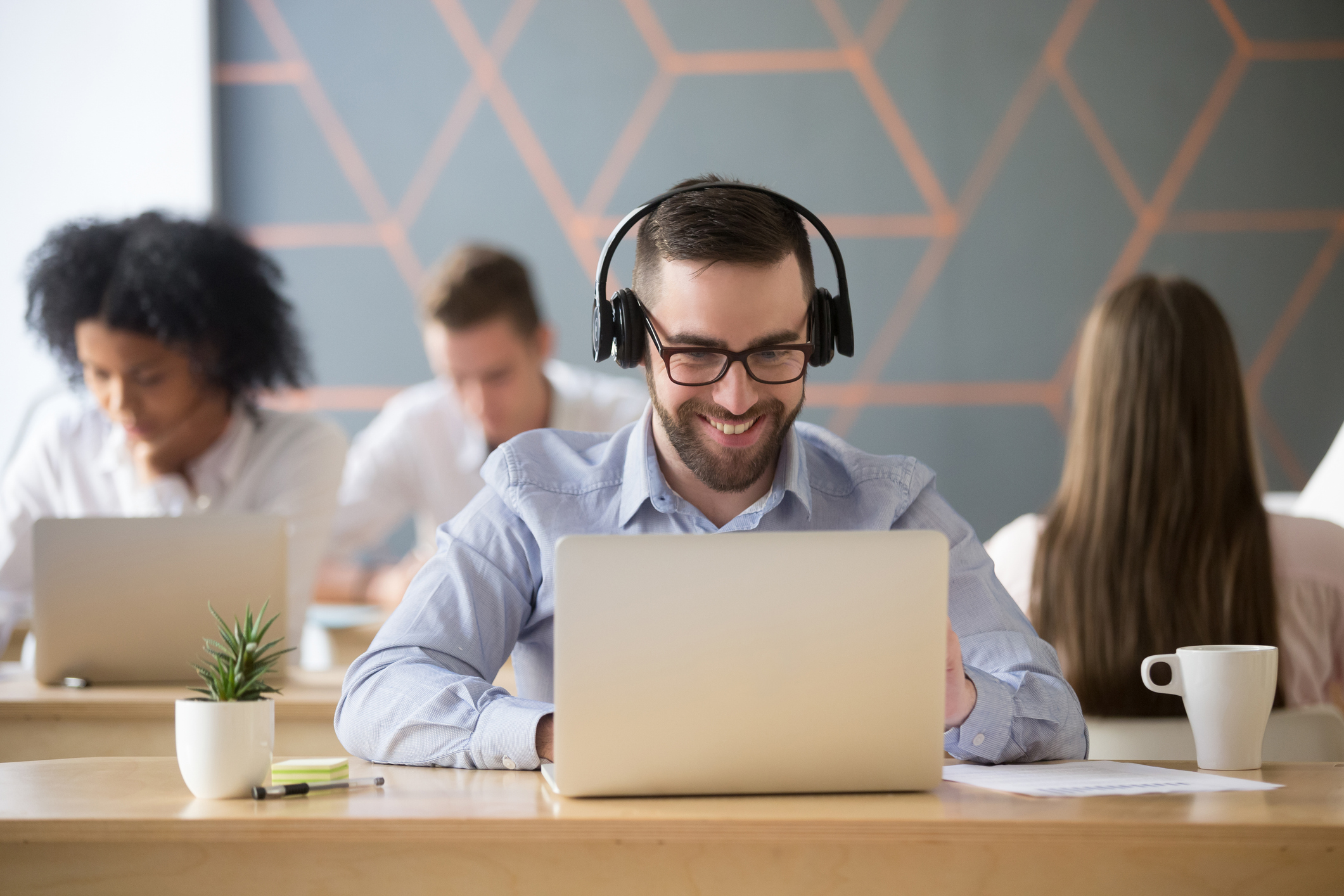 Smiling businessman listening to music while sitting at a laptop