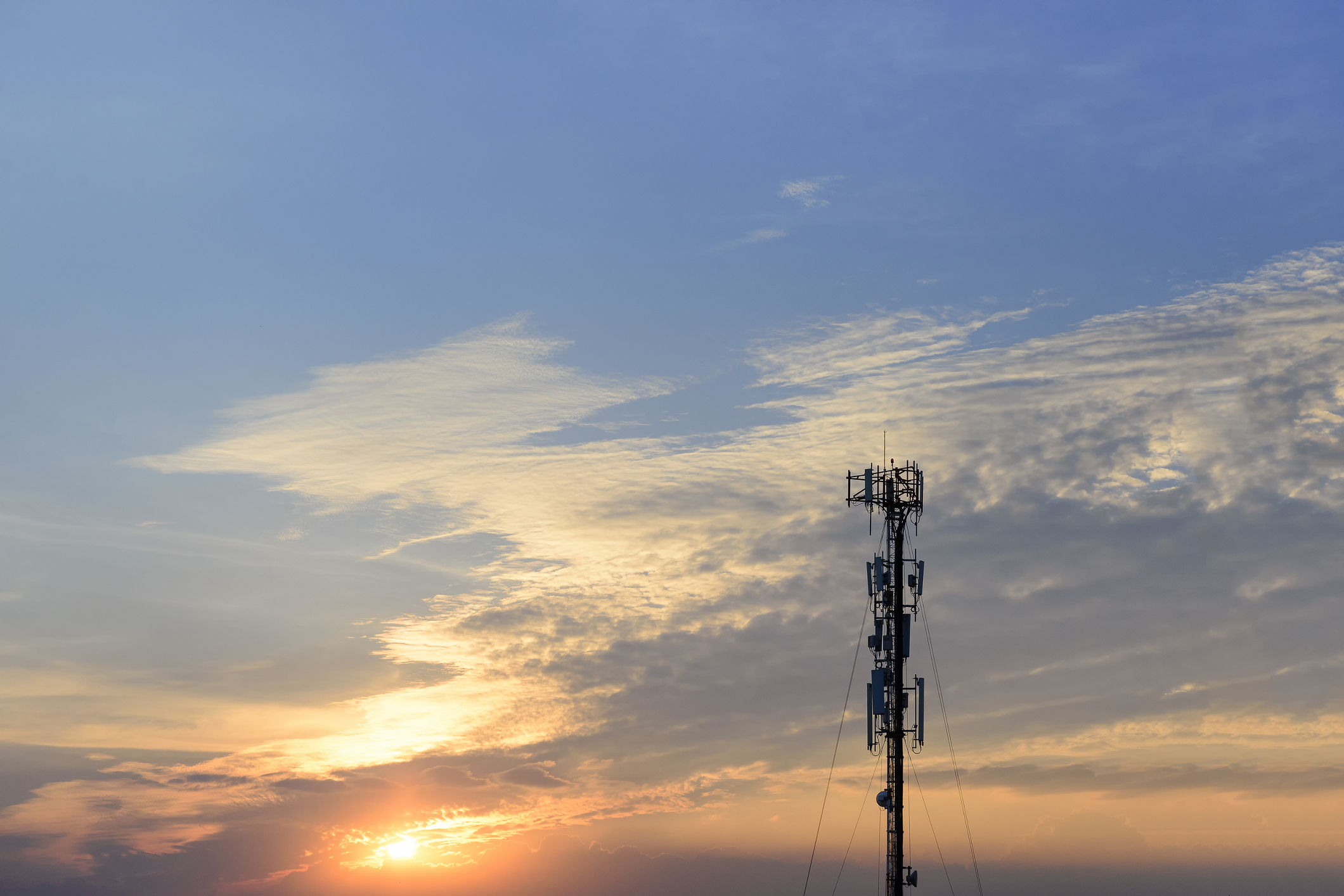 A cell tower with the sun setting in the background.