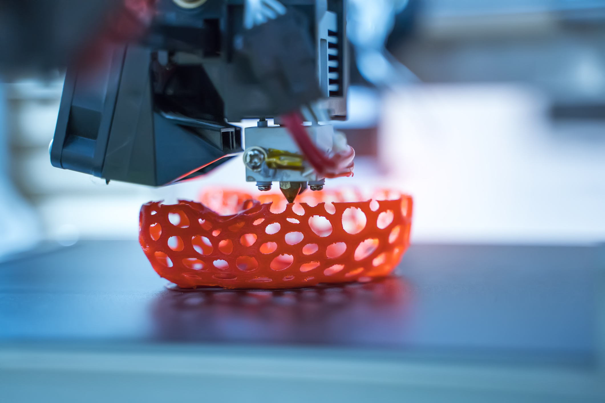 3D printer creating a sponge-like bowl shape with red-orange filament.
