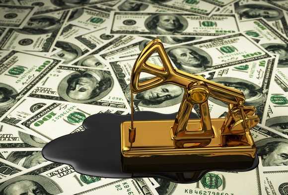 A dinosaur oil well paper weigh sitting on a pile of $100 bills.