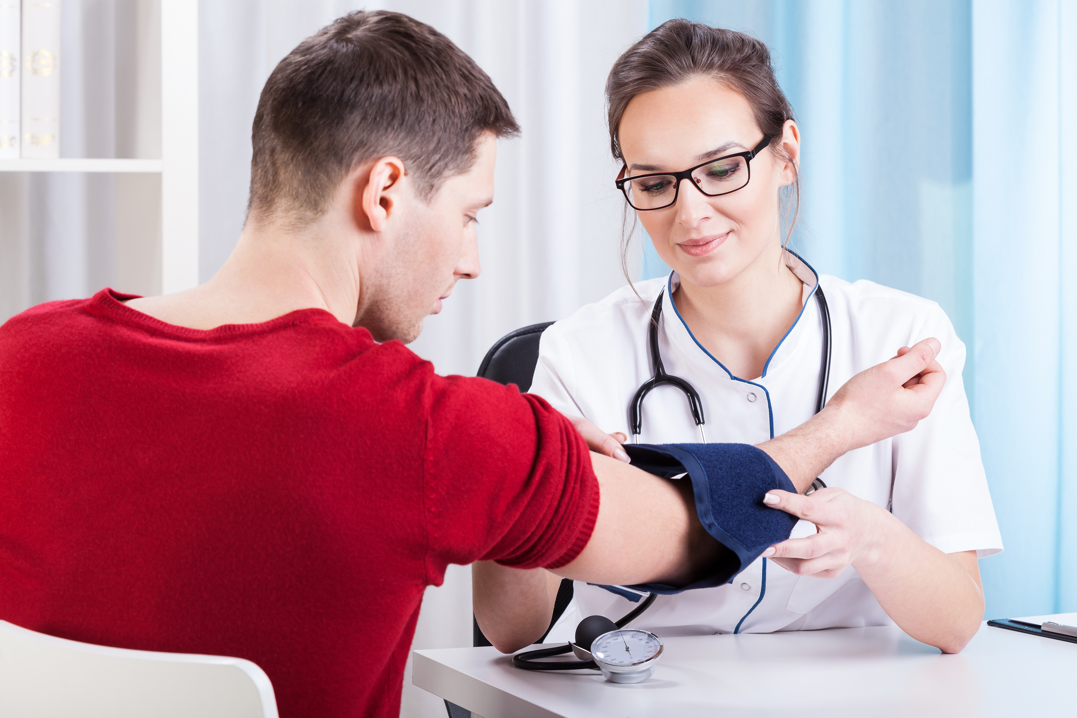 Doctor taking blood pressure of male adult.