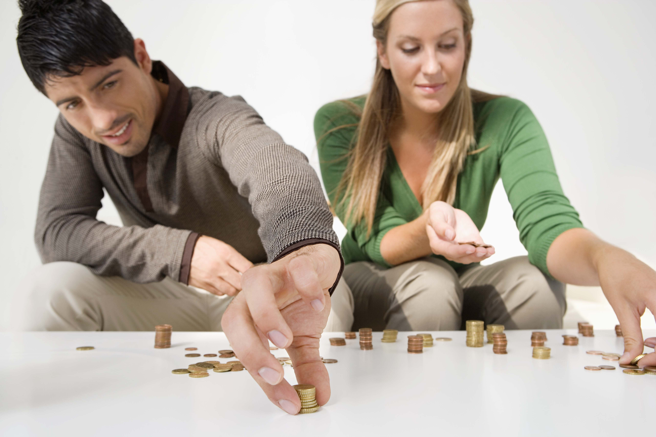 A millennial couple counting coins on a table.