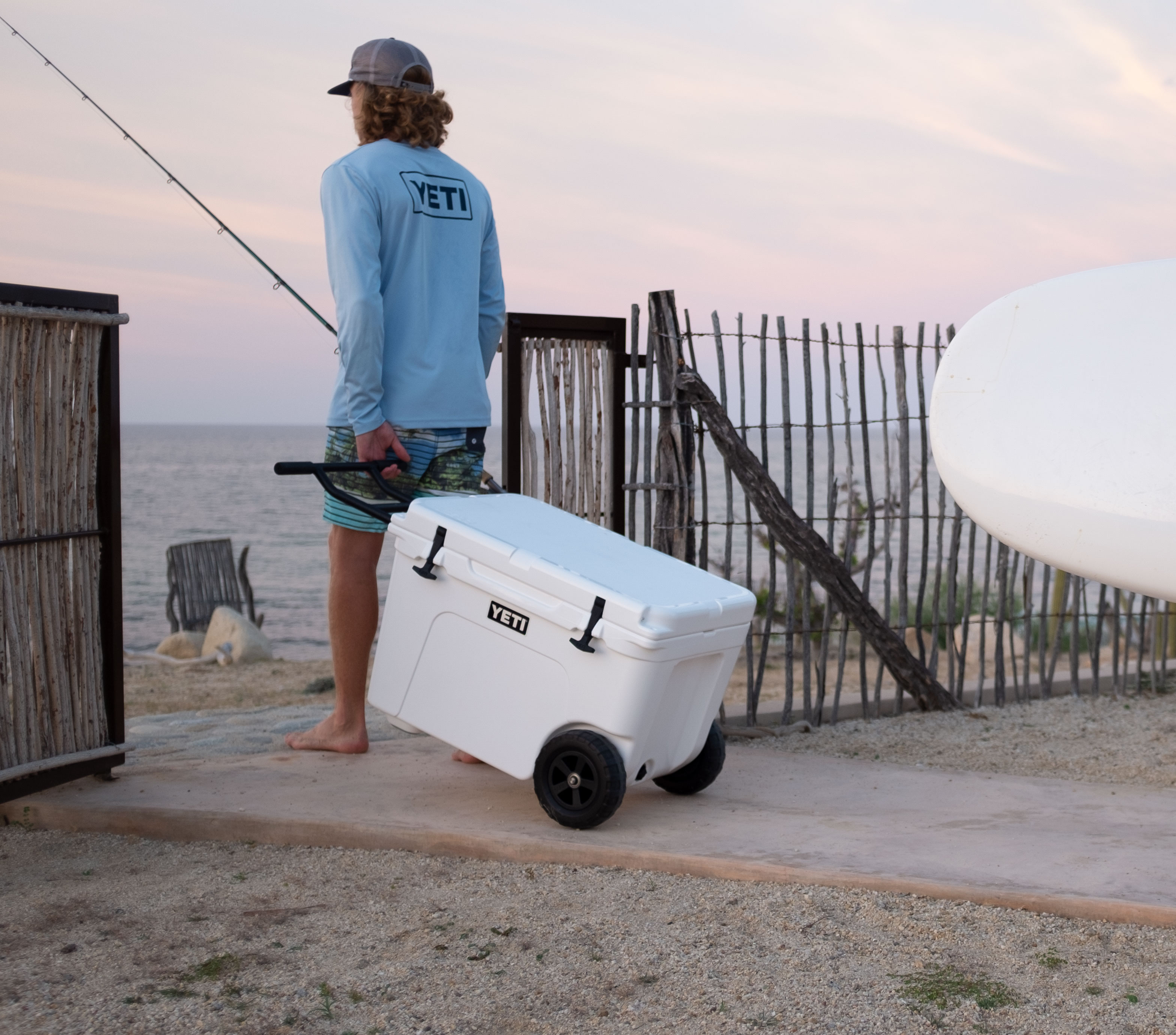A man rolling a Yeti cooler down to the beach.