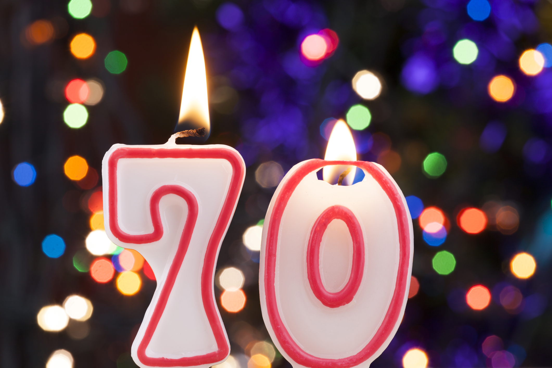 We see two candles on a birthday cake -- spelling the number 70.