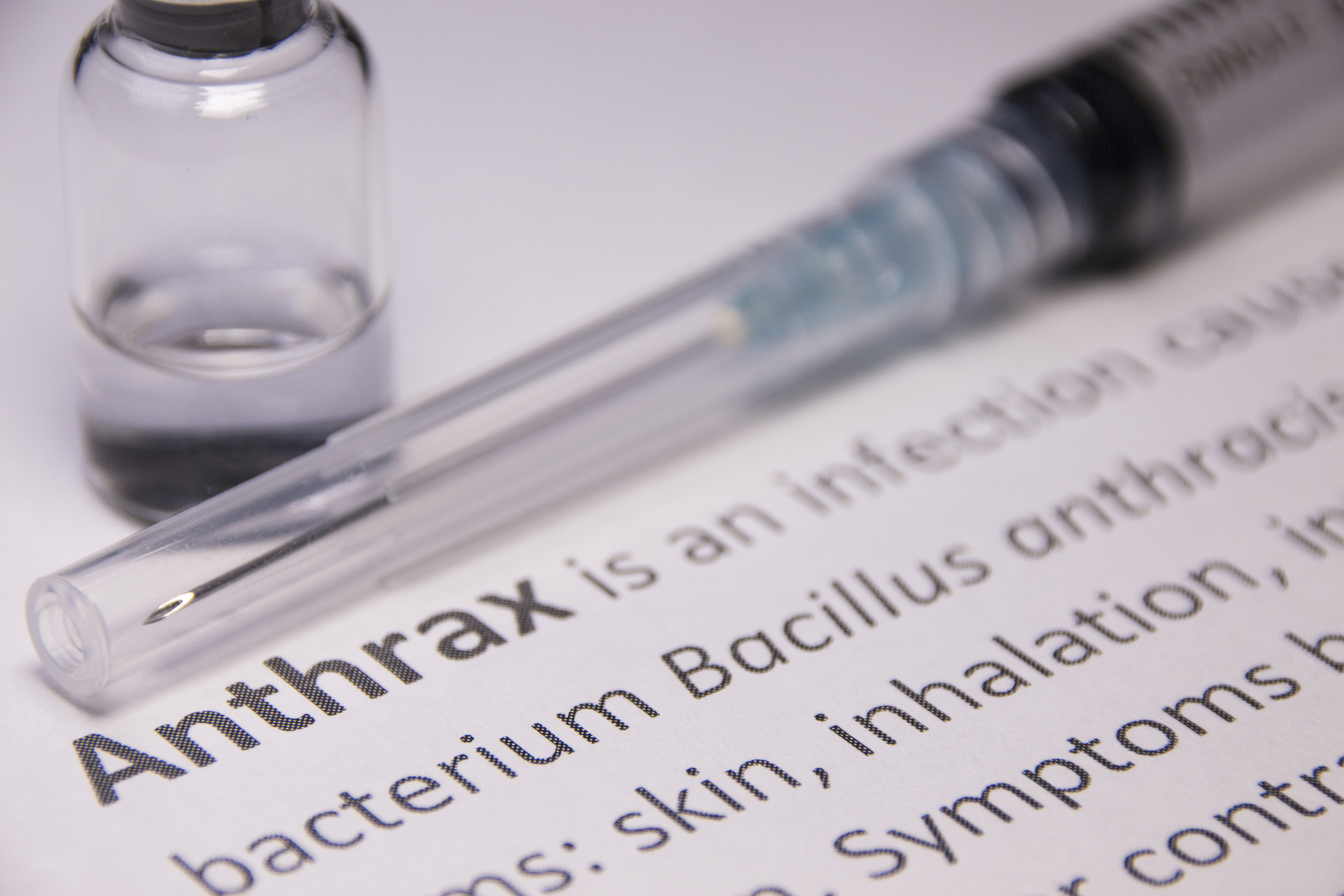 Paper with definition of anthrax with a needle and vial nearby.