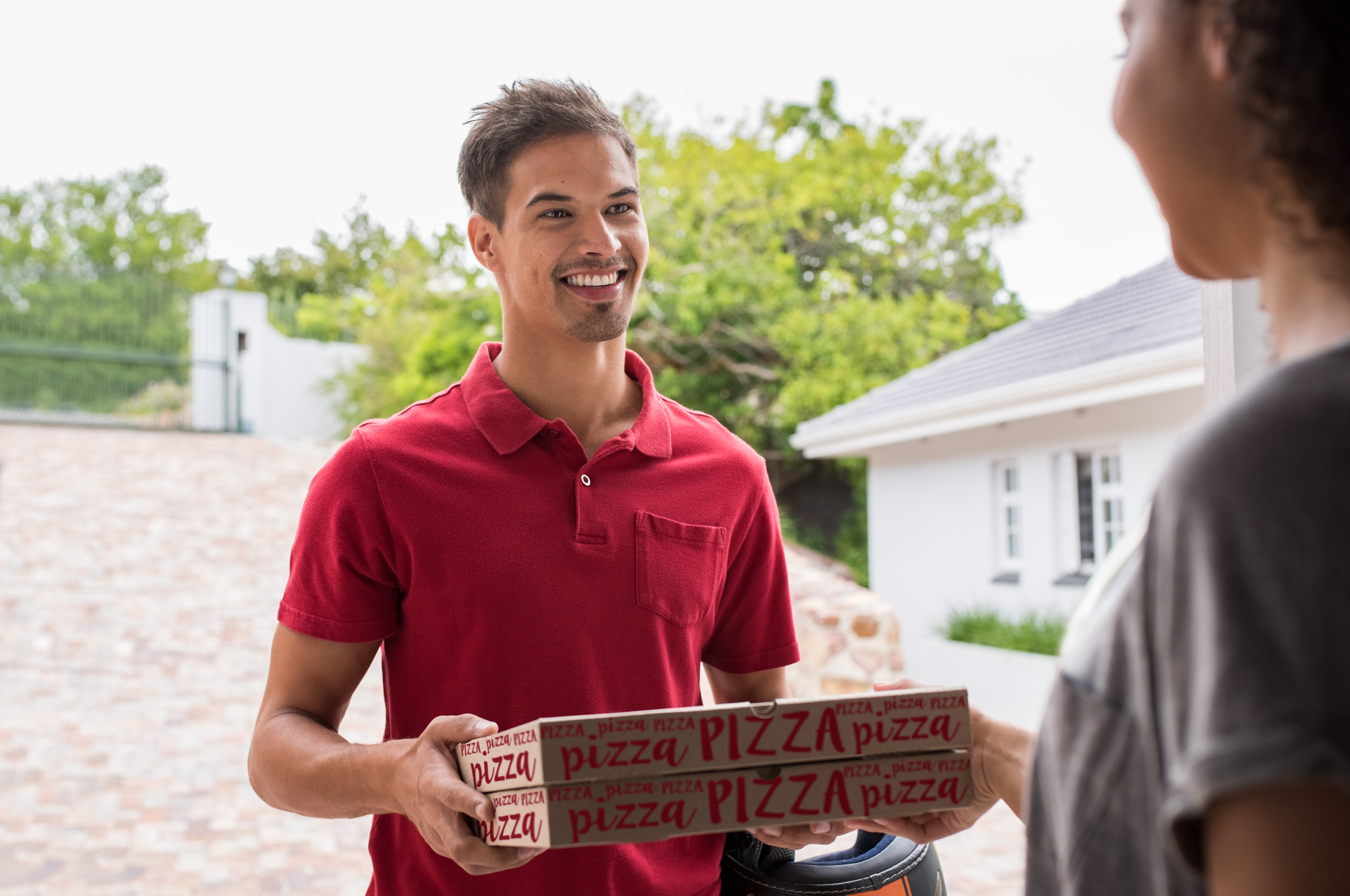 Smiling man handing two pizza boxes to a woman.