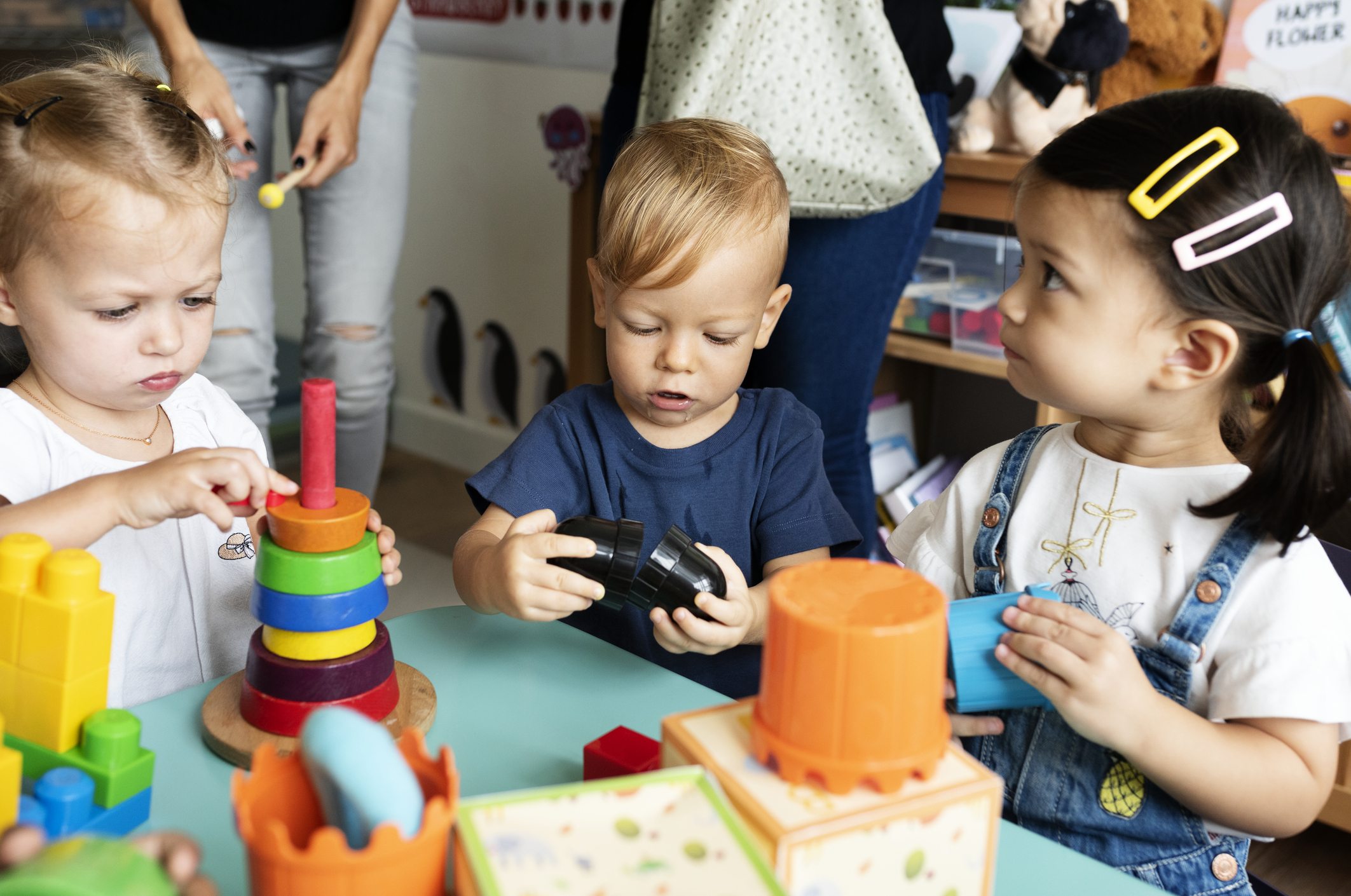 Three infants at a table, playing with toys