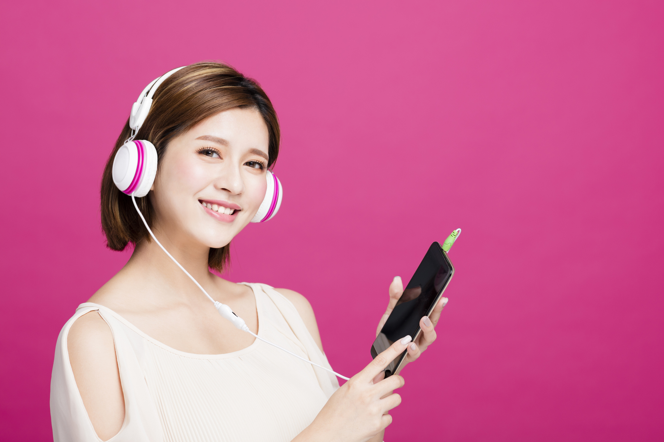 A young woman listens to music on her smartphone.