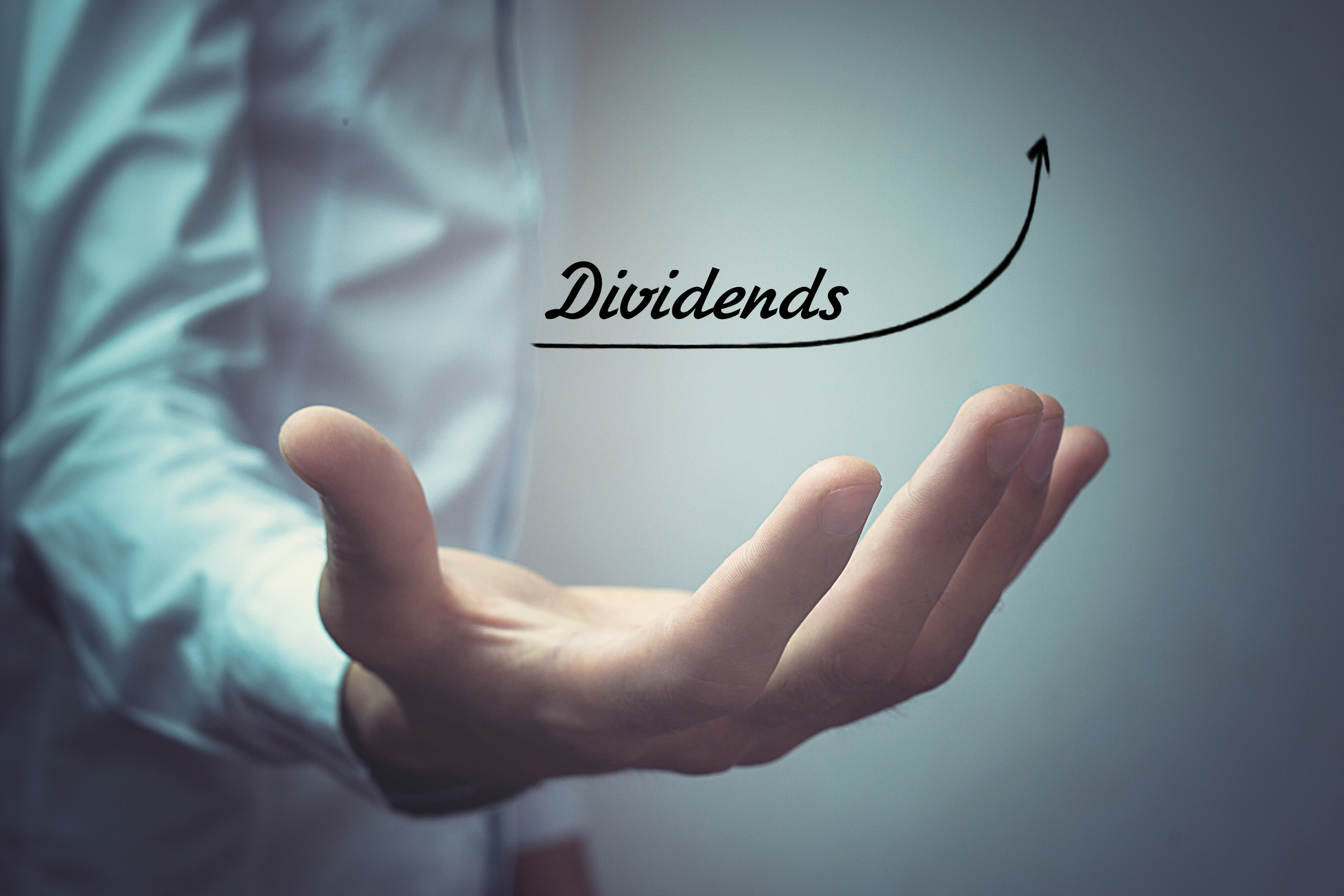 A man holding out his hand with the word dividends above and an arrow sloping upward.