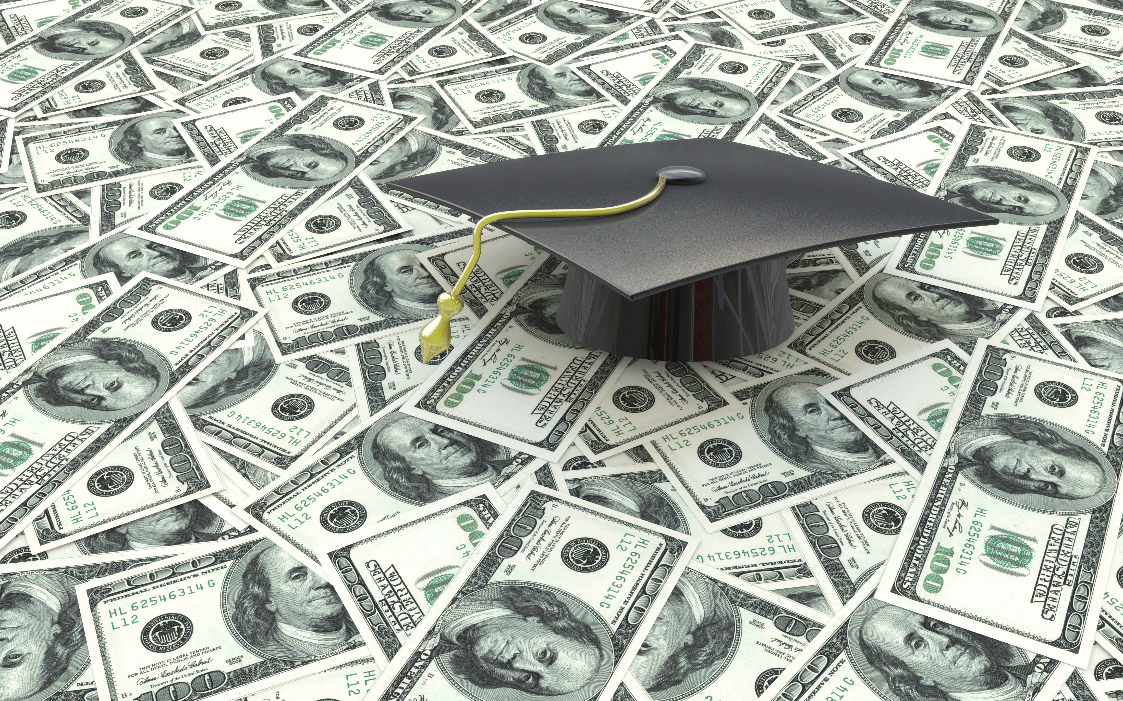 College graduation cap sitting on a bunch of cash