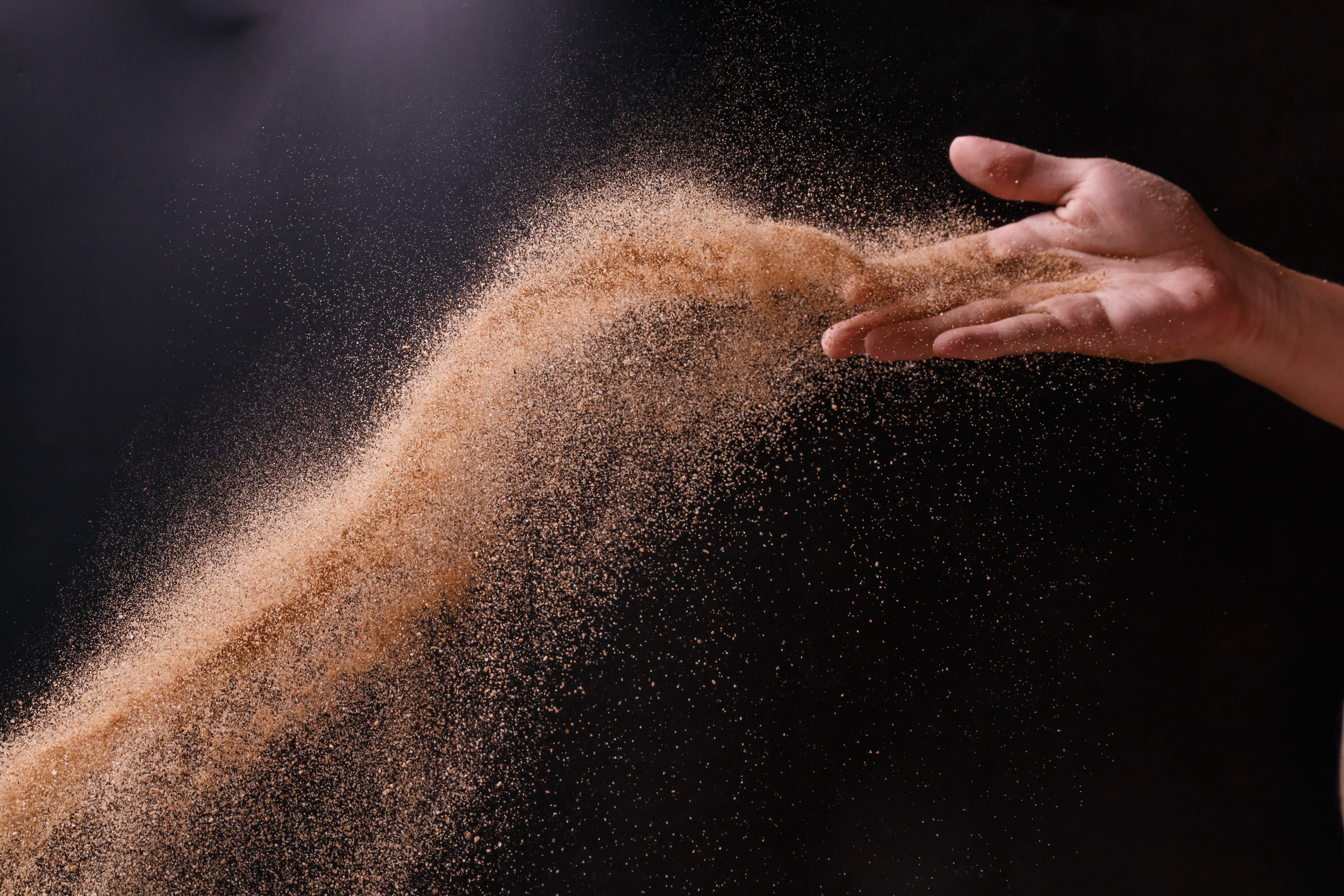 A hand scattering ashes.