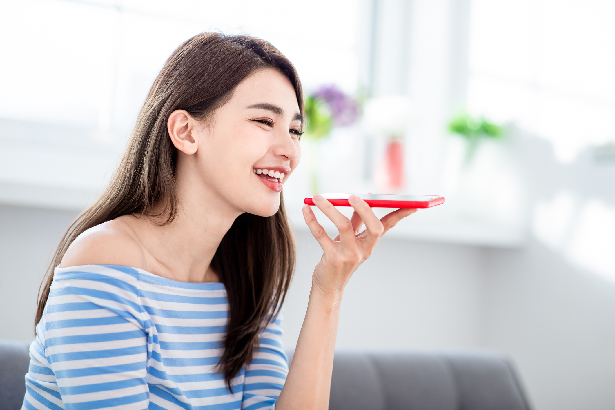 A young woman speaks to her smartphone.