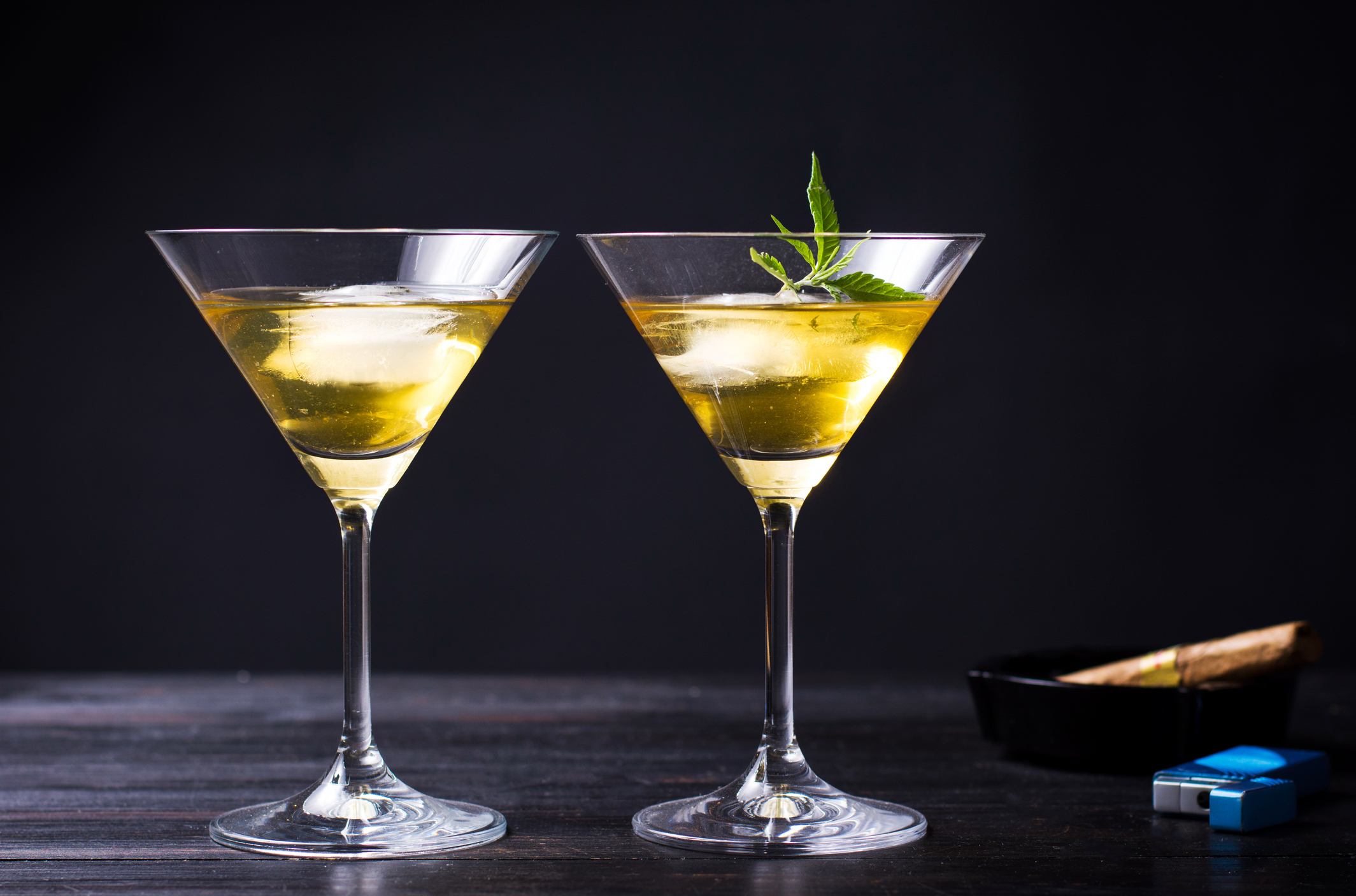 Two cocktails, one with a marijuana leaf in it.