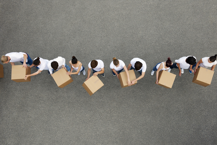 A line of people passing boxes from one end to the other.