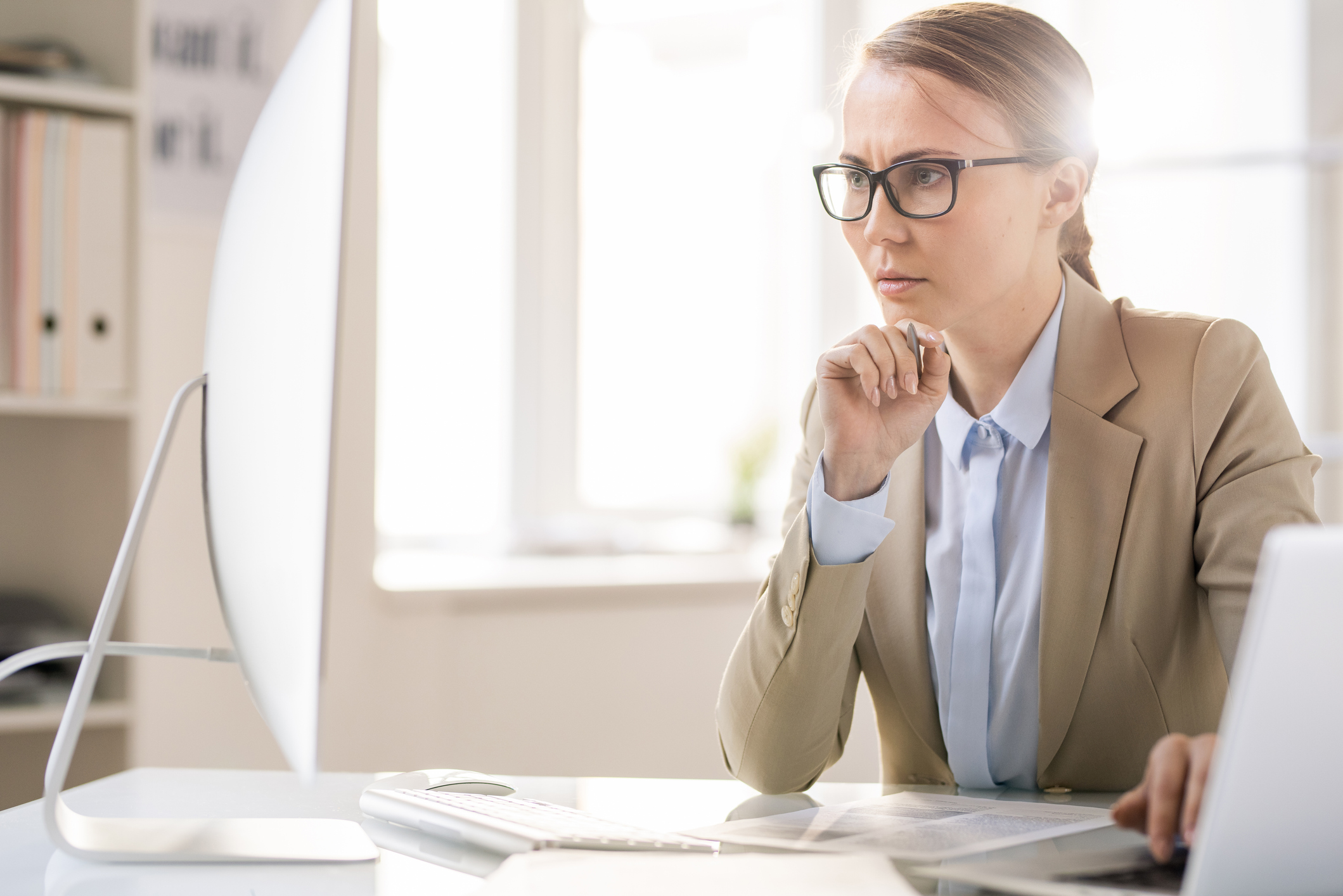 Professionally dressed woman with serious expression looking at computer monitor