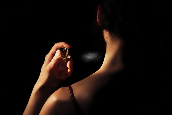 A woman spraying herself with perfume.