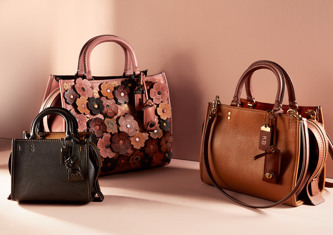 Three leather Coach purses with a beige background.