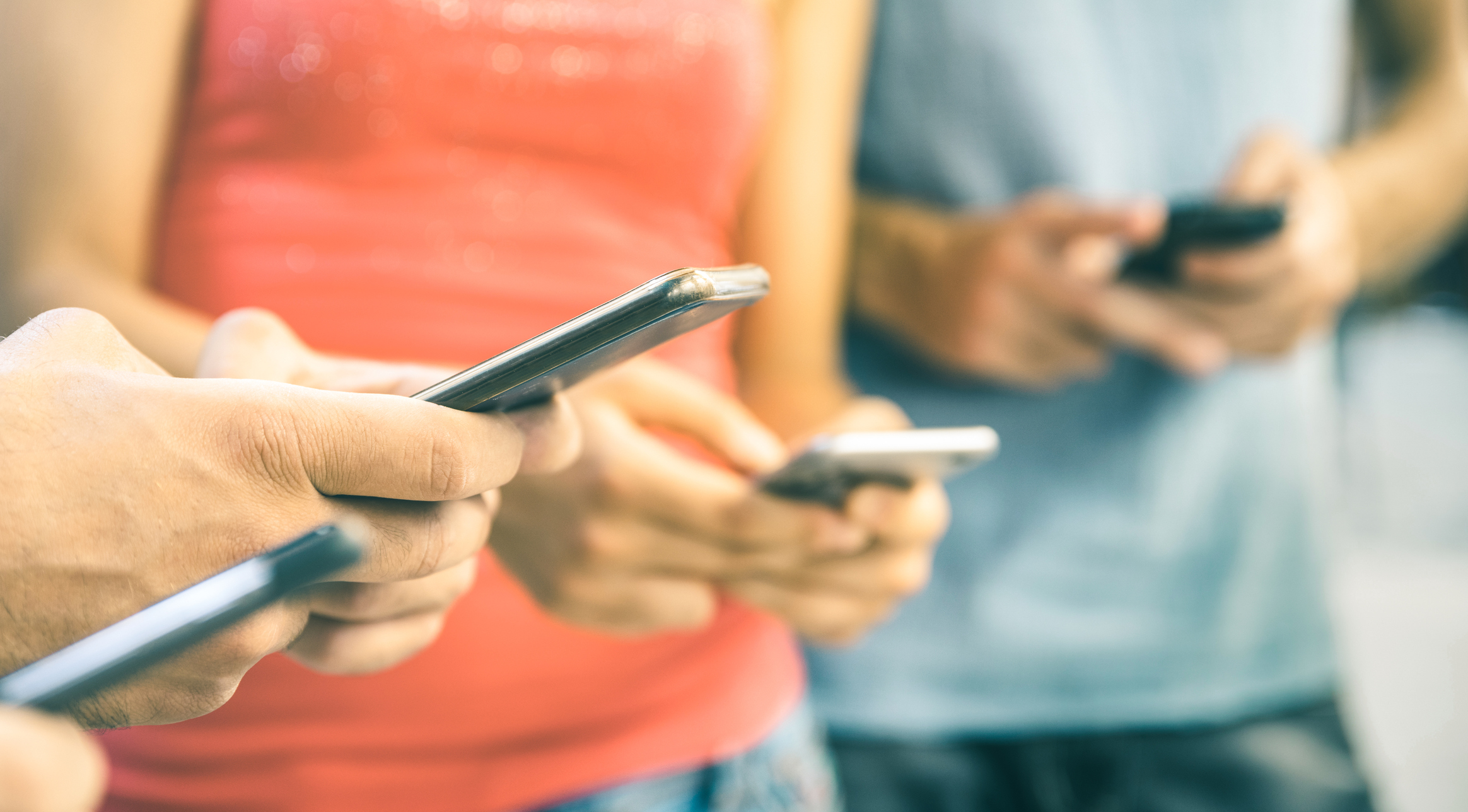 A group of people use their smartphones.